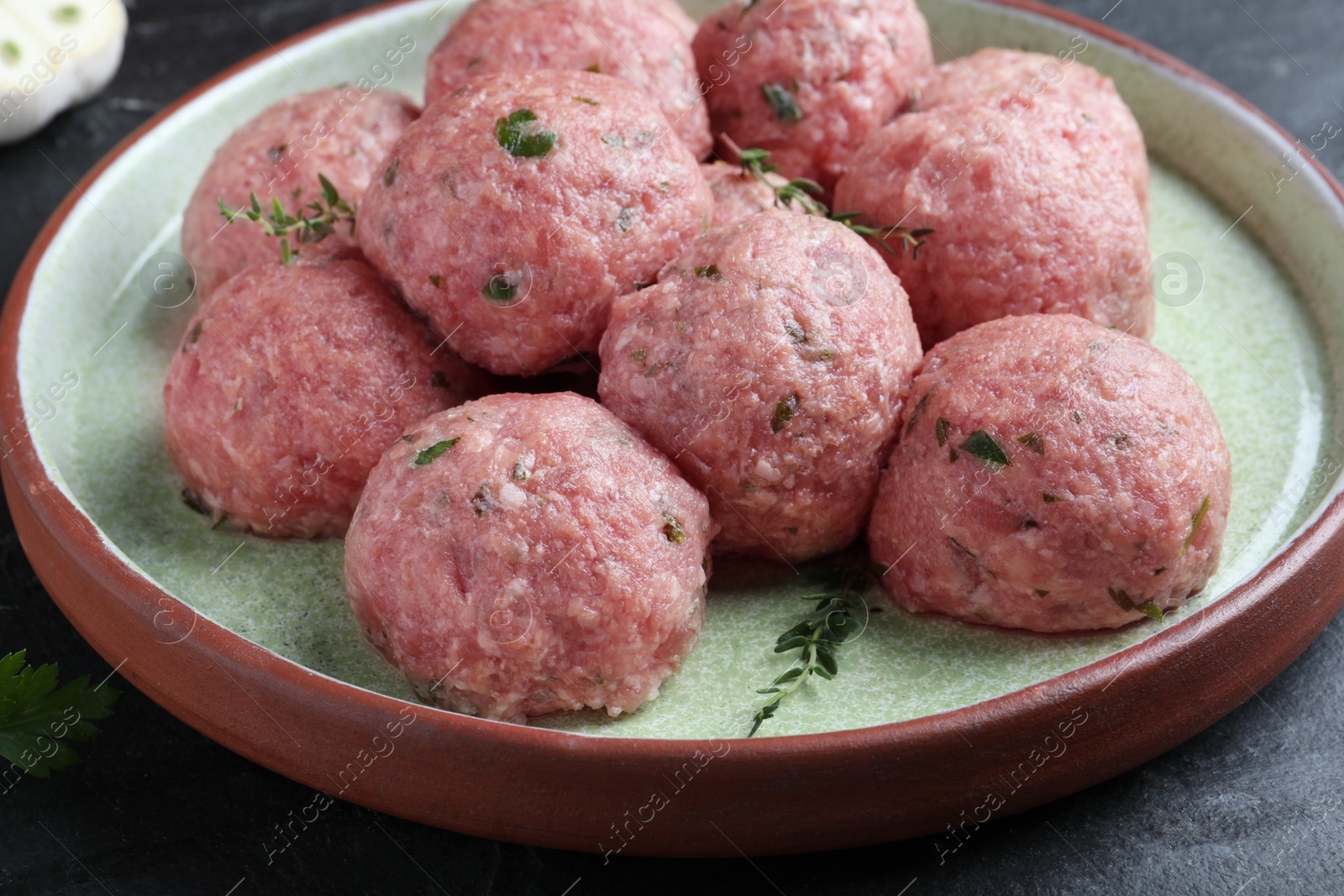 Photo of Many fresh raw meatballs on black table, closeup