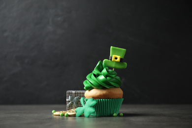 Photo of Decorated cupcake and gift box on grey table. St. Patrick's Day celebration