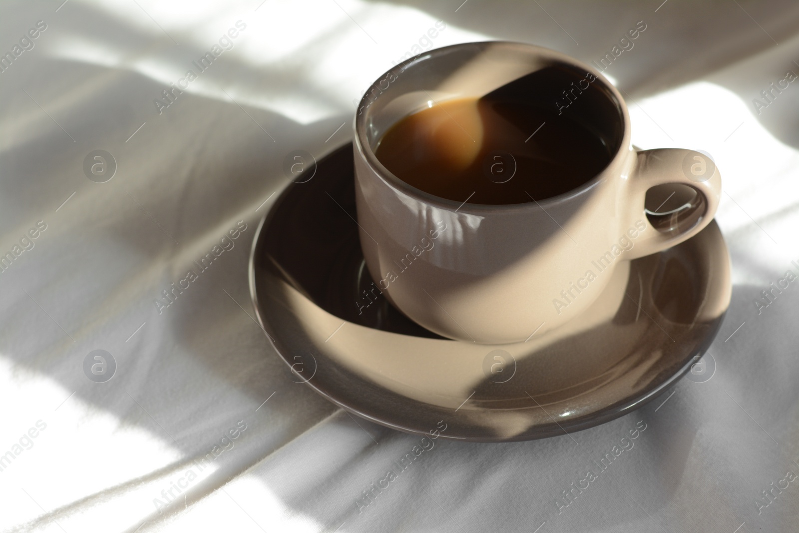 Photo of Cup of aromatic coffee on bed in morning, closeup