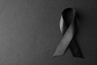 Photo of Black ribbon on dark background, top view with space for text. Funeral symbol