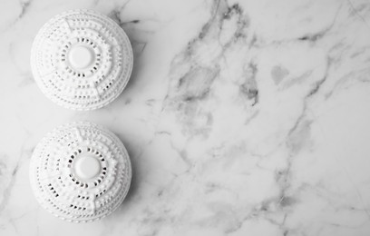 Photo of Laundry dryer balls on white marble table, flat lay. Space for text