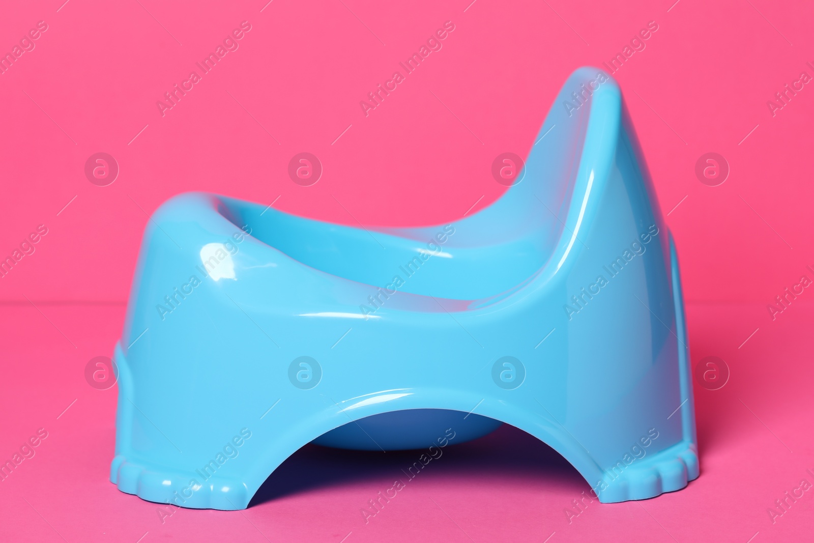 Photo of Light blue baby potty on pink background. Toilet training