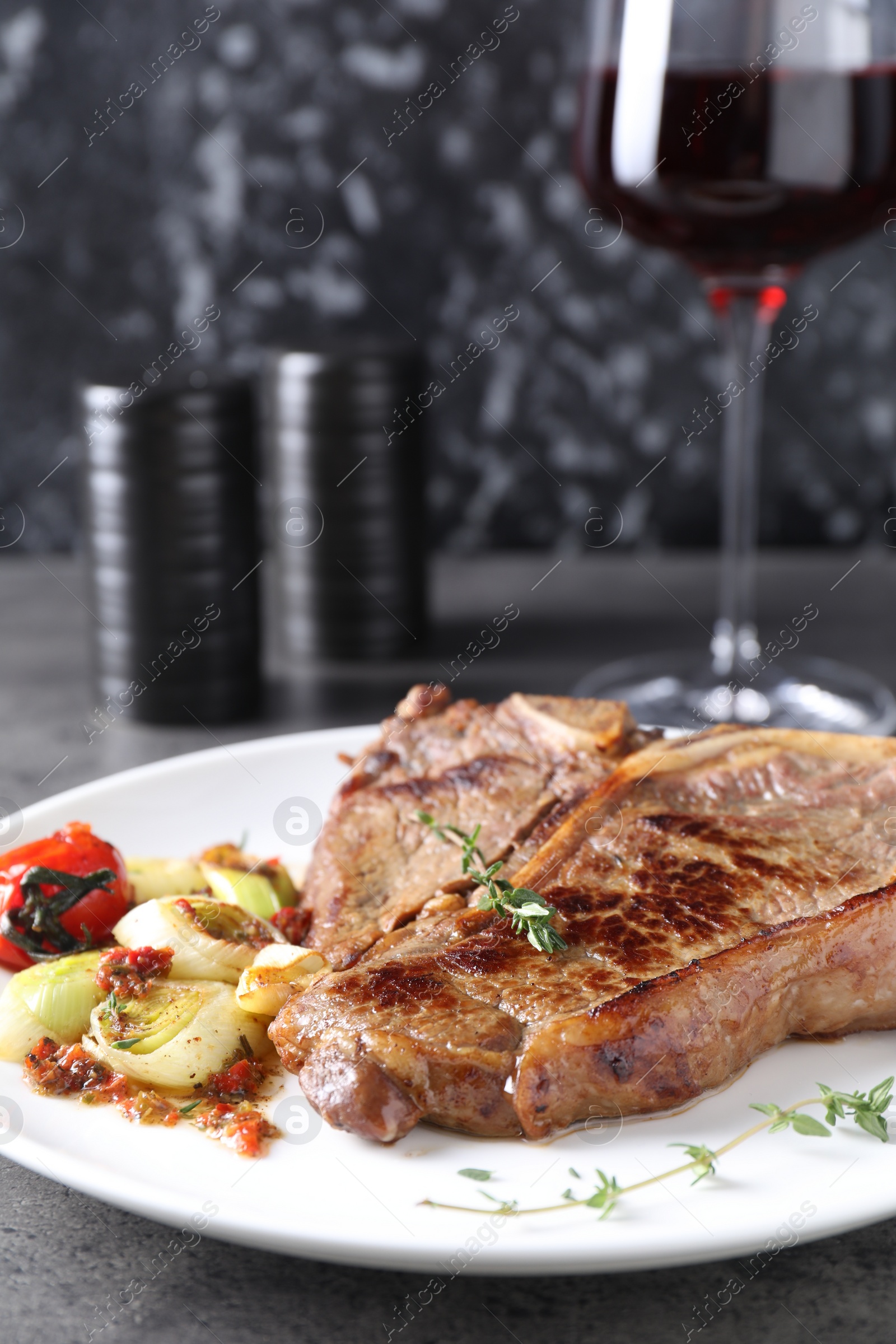 Photo of Delicious fried beef meat and vegetables on grey table