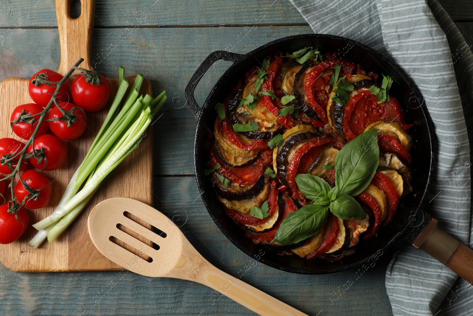 Photo of Delicious ratatouille and ingredients on light blue wooden table, flat lay