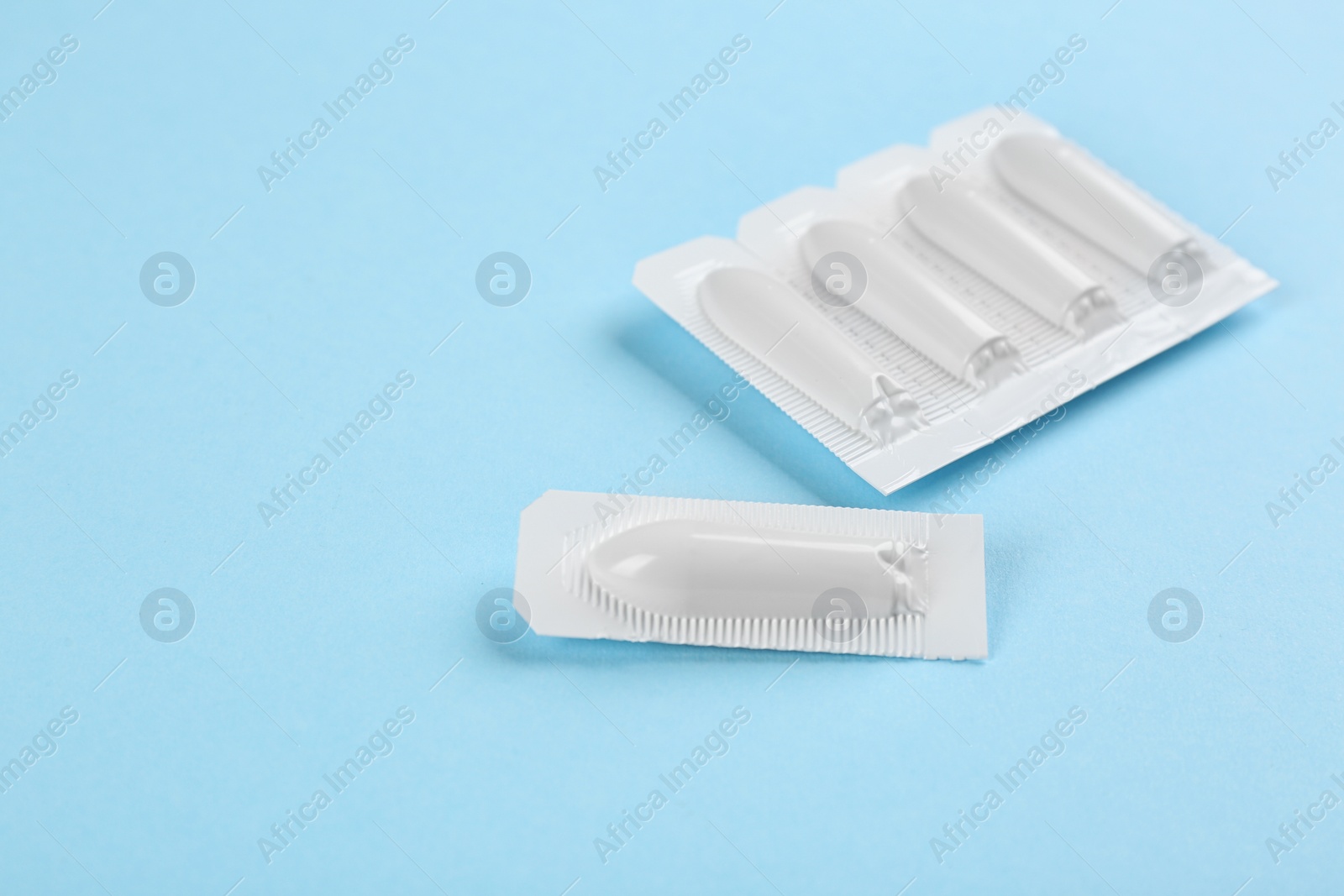Photo of Suppositories on light blue background. Hemorrhoid treatment