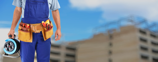 Closeup view of electrician with tools at site, space for text. Banner design