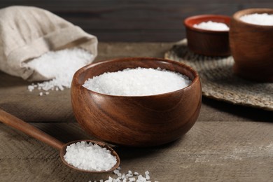 Photo of Bowl and spoon with natural sea salt on wooden table