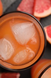 Photo of Tasty grapefruit drink with ice in glass on table, top view