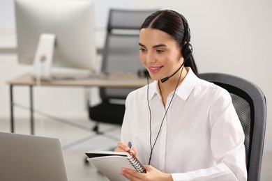 Photo of Hotline operator with headset working on laptop in office