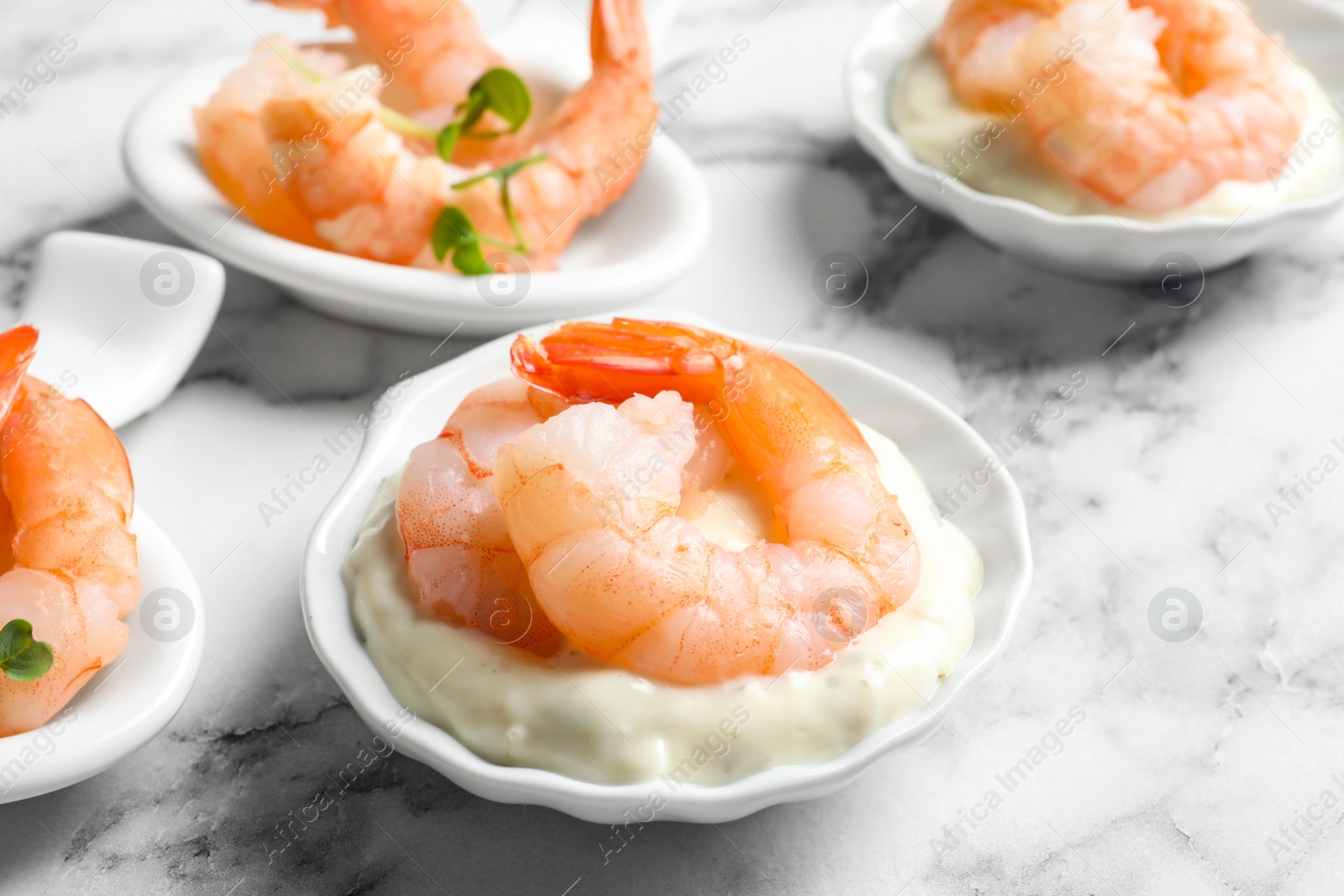 Photo of Bowls with boiled shrimps and sauce on light background