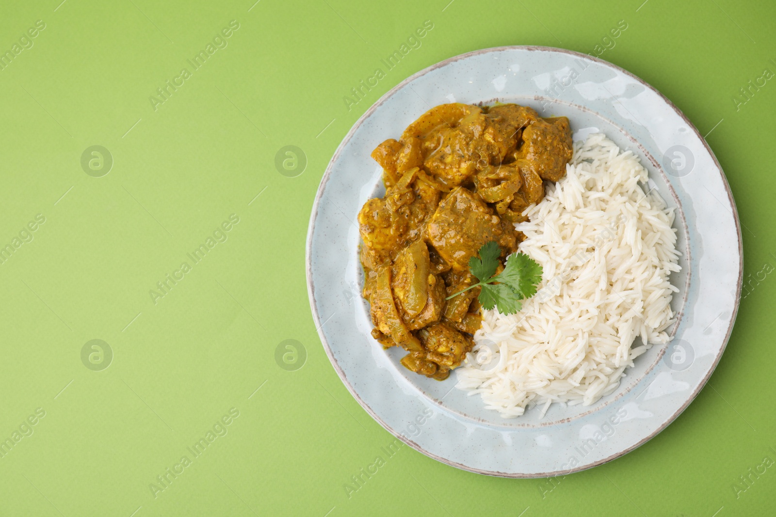 Photo of Delicious chicken curry with rice on green background, top view. Space for text