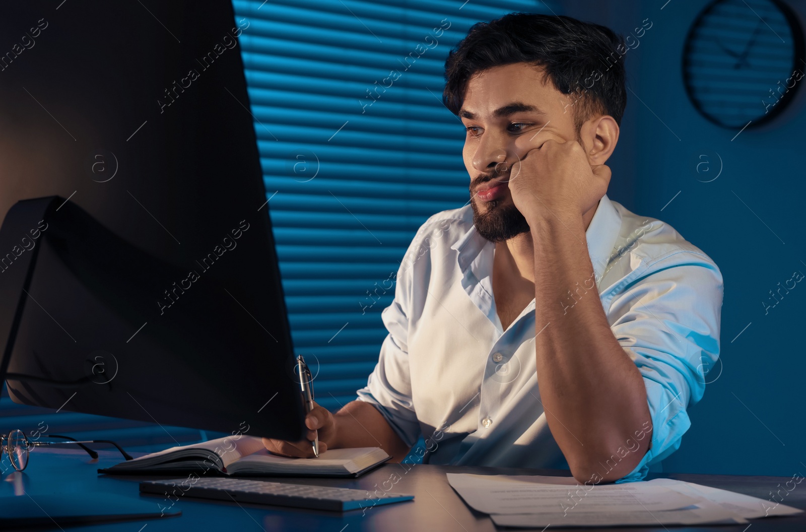 Photo of Tired young man working late in office