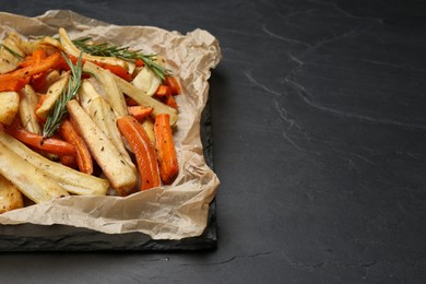 Photo of Parchment with tasty baked parsnip and bell pepper on dark grey table, space for text