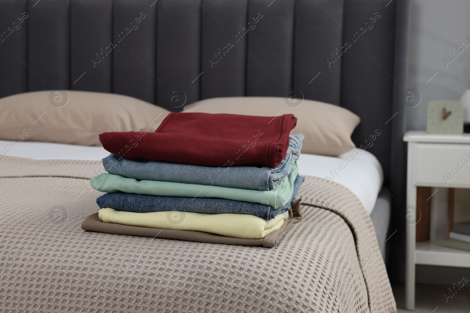 Photo of Stack of different folded clothes on bed at home