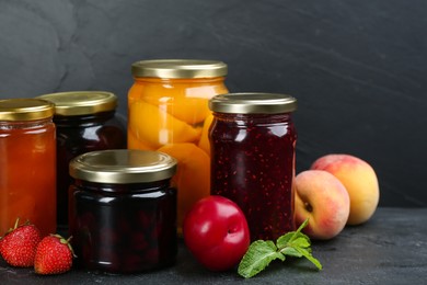 Jars of pickled fruits and jams on grey table