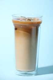 Photo of Glass of iced coffee on light blue background