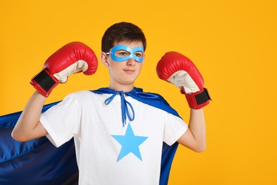 Teenage boy in superhero costume on yellow background