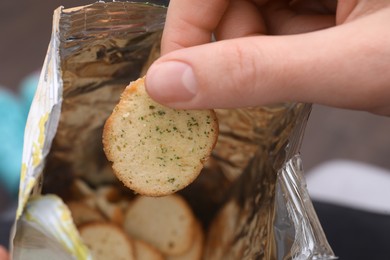 Photo of Woman taking crispy rusk out of package, closeup