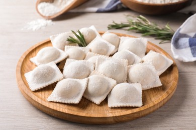 Photo of Uncooked ravioli and rosemary on white wooden table