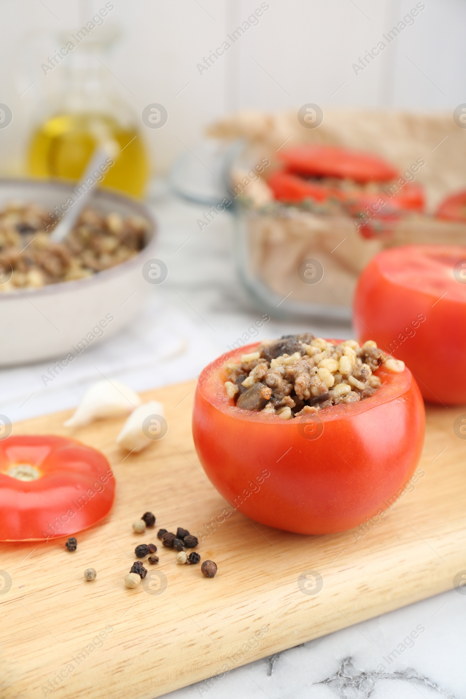 Photo of Preparing stuffed tomatoes with minced beef, bulgur and mushrooms on white marble table, closeup