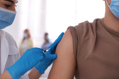 Photo of Doctor giving injection to patient in hospital, closeup. Vaccination campaign