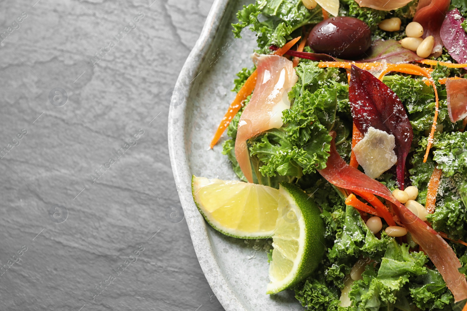 Photo of Tasty fresh kale salad on grey table, closeup