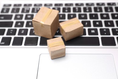Photo of Internet shopping. Small cardboard boxes on laptop, closeup