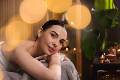 Spa therapy. Beautiful young woman lying on massage table in salon, space for text