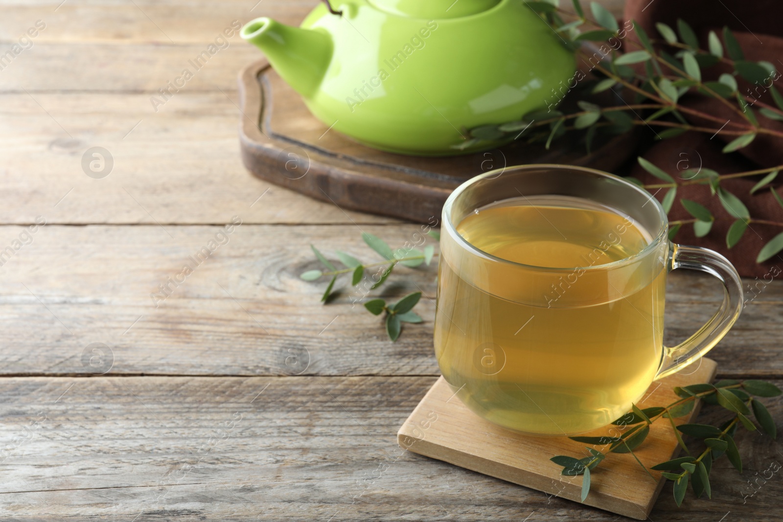 Photo of Glass cup of aromatic eucalyptus tea on wooden table. Space for text