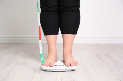 Overweight woman using scales indoors