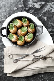 Delicious cooked snails in baking dish served on grey textured table, flat lay