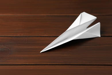 Photo of Handmade paper plane on wooden table, closeup. Space for text