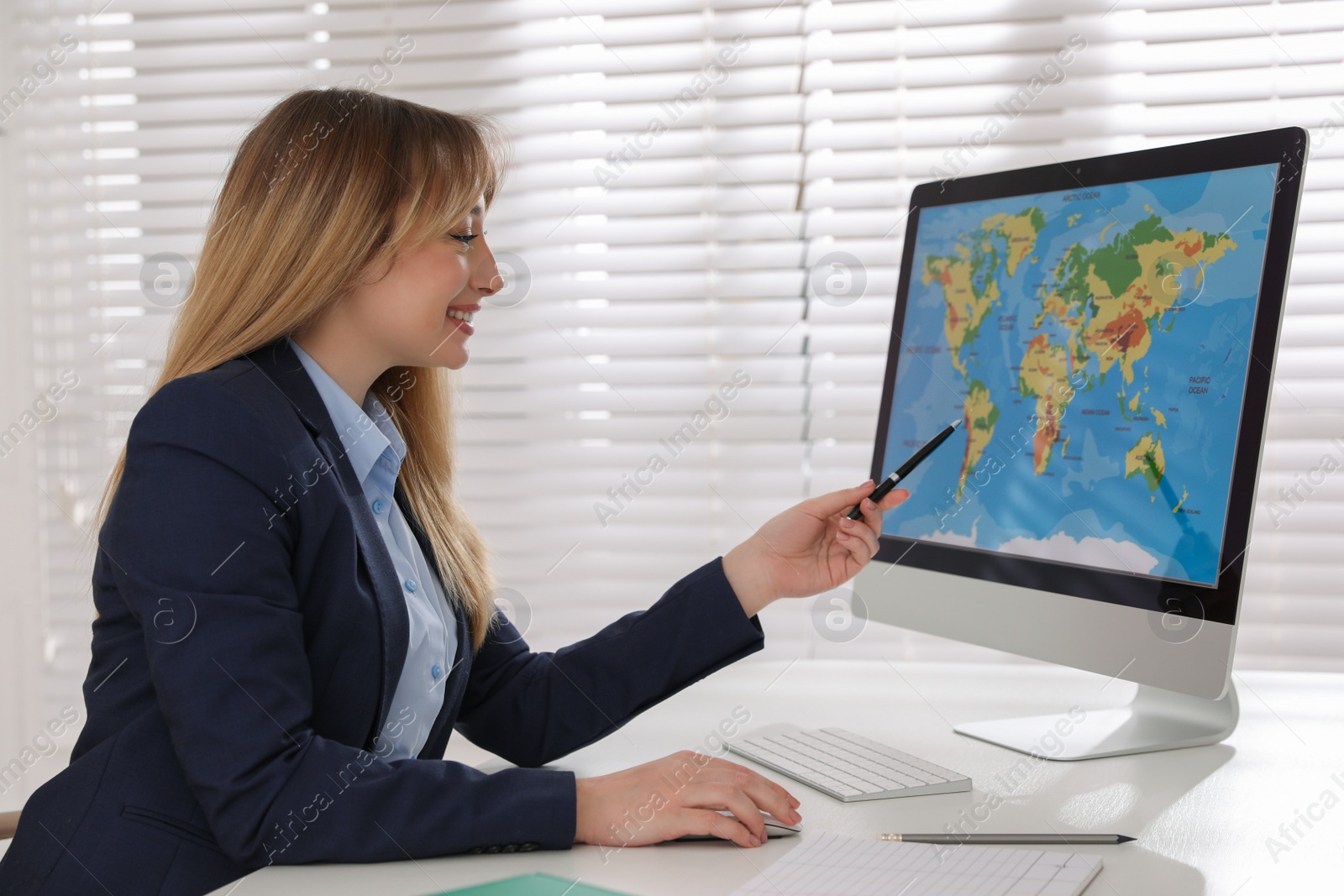 Photo of Happy manager showing world map on computer at desk in travel agency