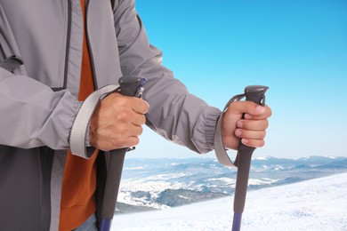 Man with trekking poles in snowy mountains, closeup