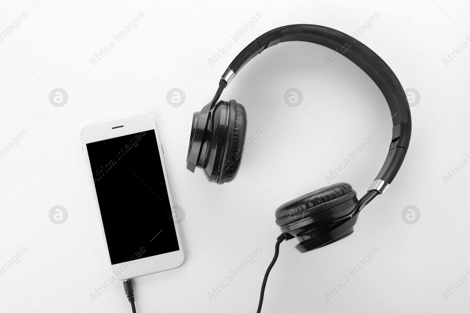 Photo of Smartphone with blank screen and headphones on white background, top view