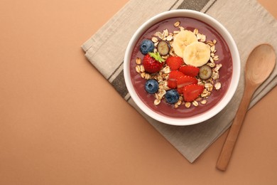 Photo of Delicious smoothie bowl with fresh berries, banana and granola on pale orange background, flat lay. Space for text