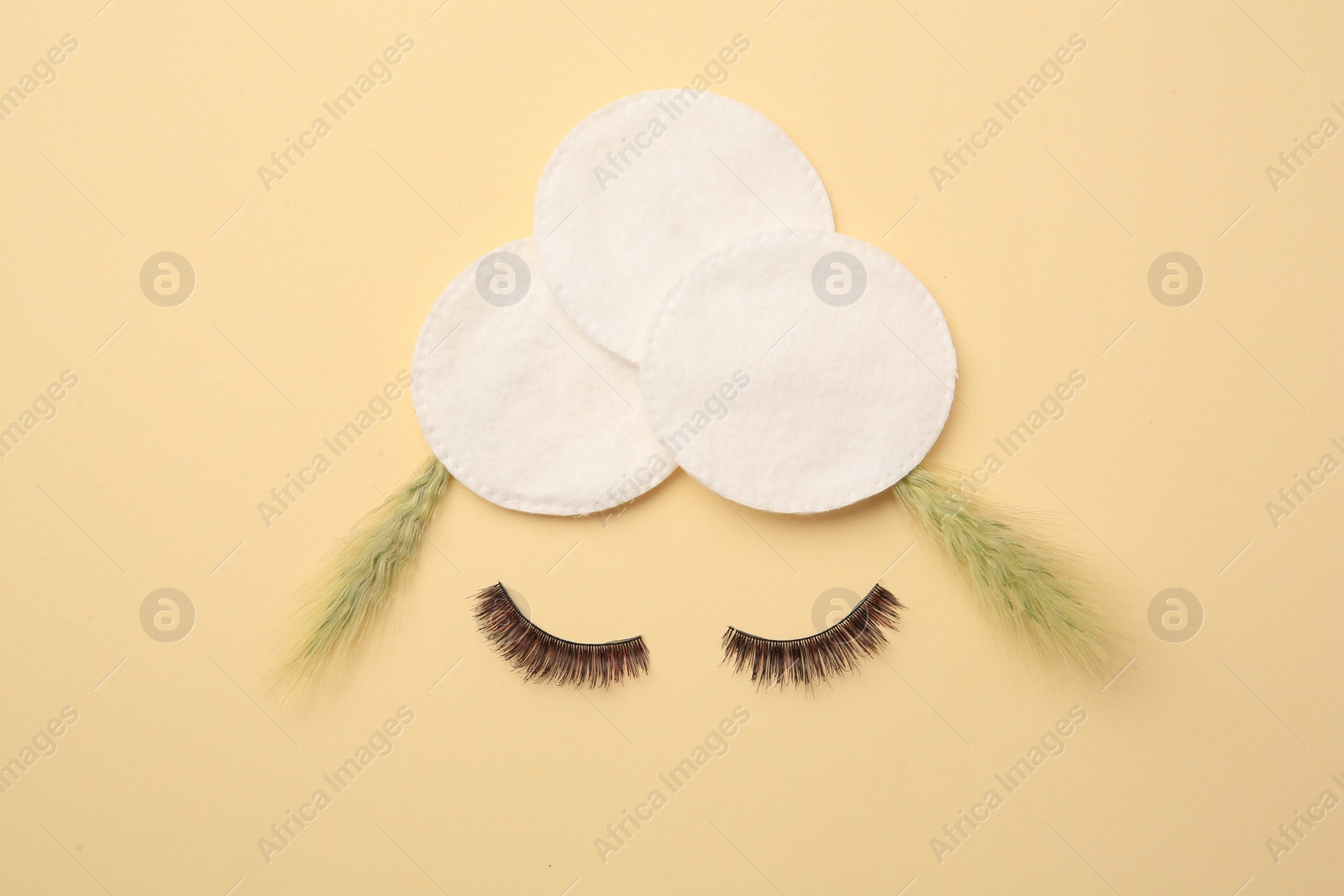 Photo of Flat lay composition with cotton pads, spikelets and false eyelashes on yellow background. Makeup removal