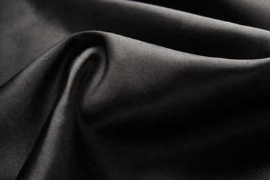 Photo of Crumpled black silk fabric as background, closeup