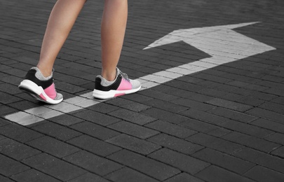 Woman going along road with arrow marking, closeup