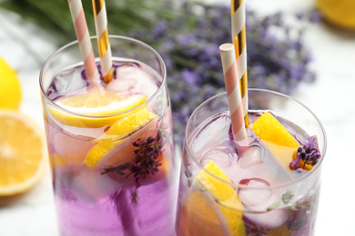 Fresh delicious lemonade with lavender and straws on white table, closeup