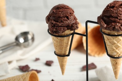 Chocolate ice cream scoops in wafer cones on stand, closeup. Space for text