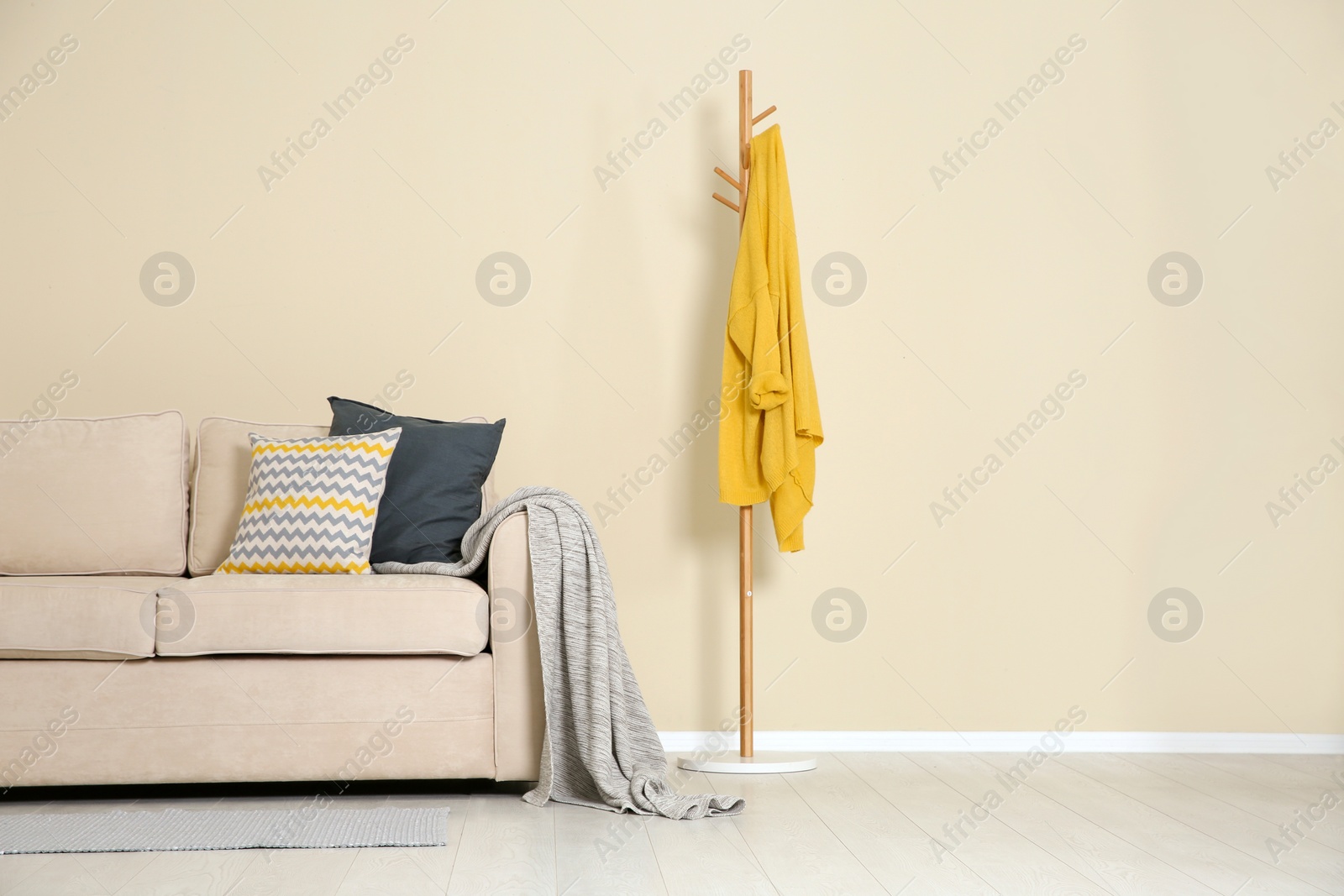 Photo of Minimalist living room interior with cozy sofa, pillows and plaid near light wall. Space for text