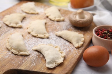 Raw dumplings (varenyky) with tasty filling on wooden board, closeup. Traditional Ukrainian dish