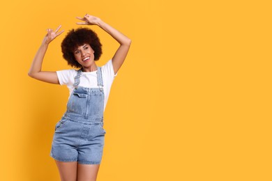 Photo of Happy young woman dancing on orange background. Space for text