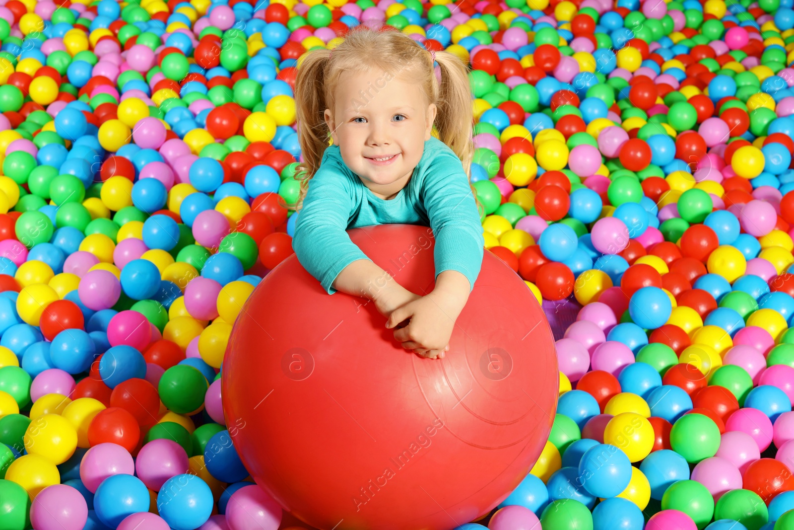 Photo of Cute child playing in ball pit indoors