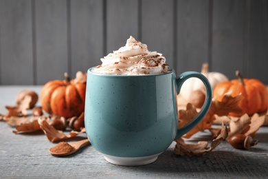 Photo of Delicious pumpkin latte on grey wooden table, closeup