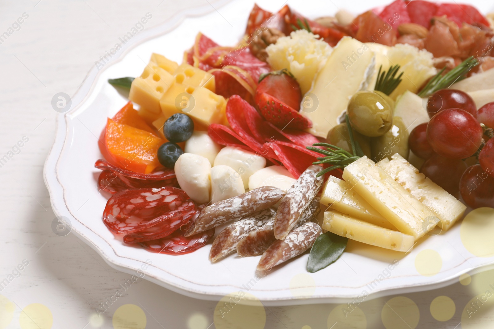 Photo of Plate full of assorted appetizers on white table, closeup