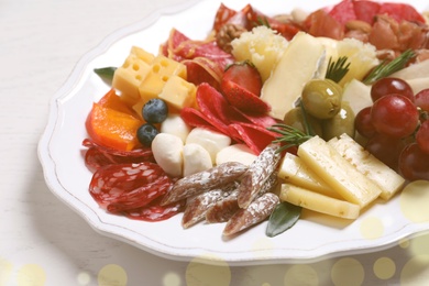 Photo of Plate full of assorted appetizers on white table, closeup