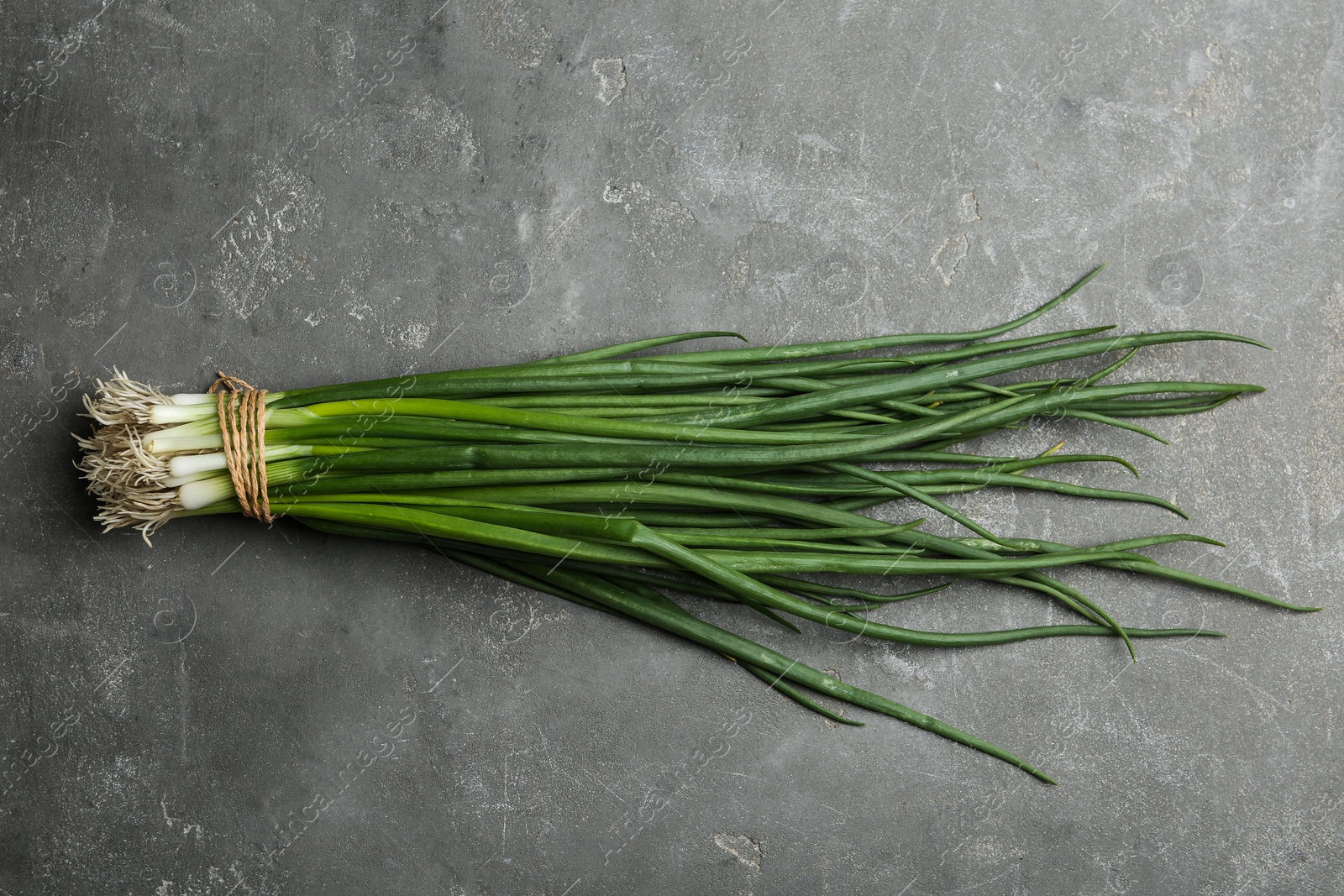 Photo of Fresh green spring onions on grey table, top view