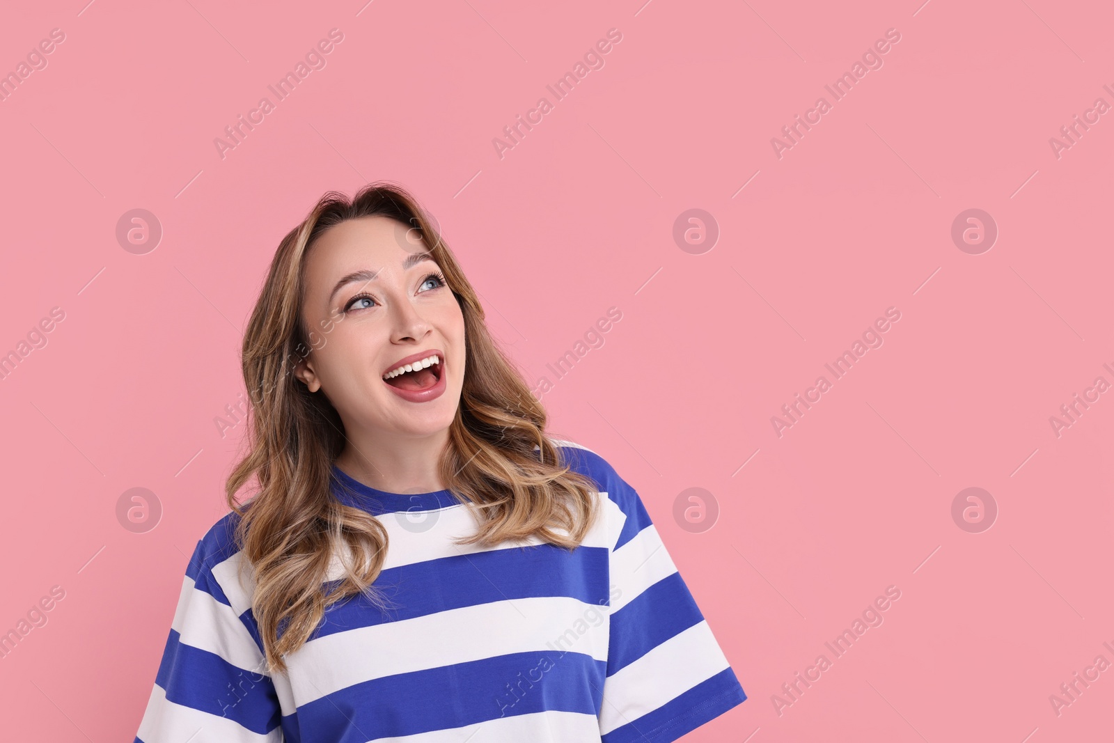 Photo of Portrait of happy surprised woman on pink background. Space for text